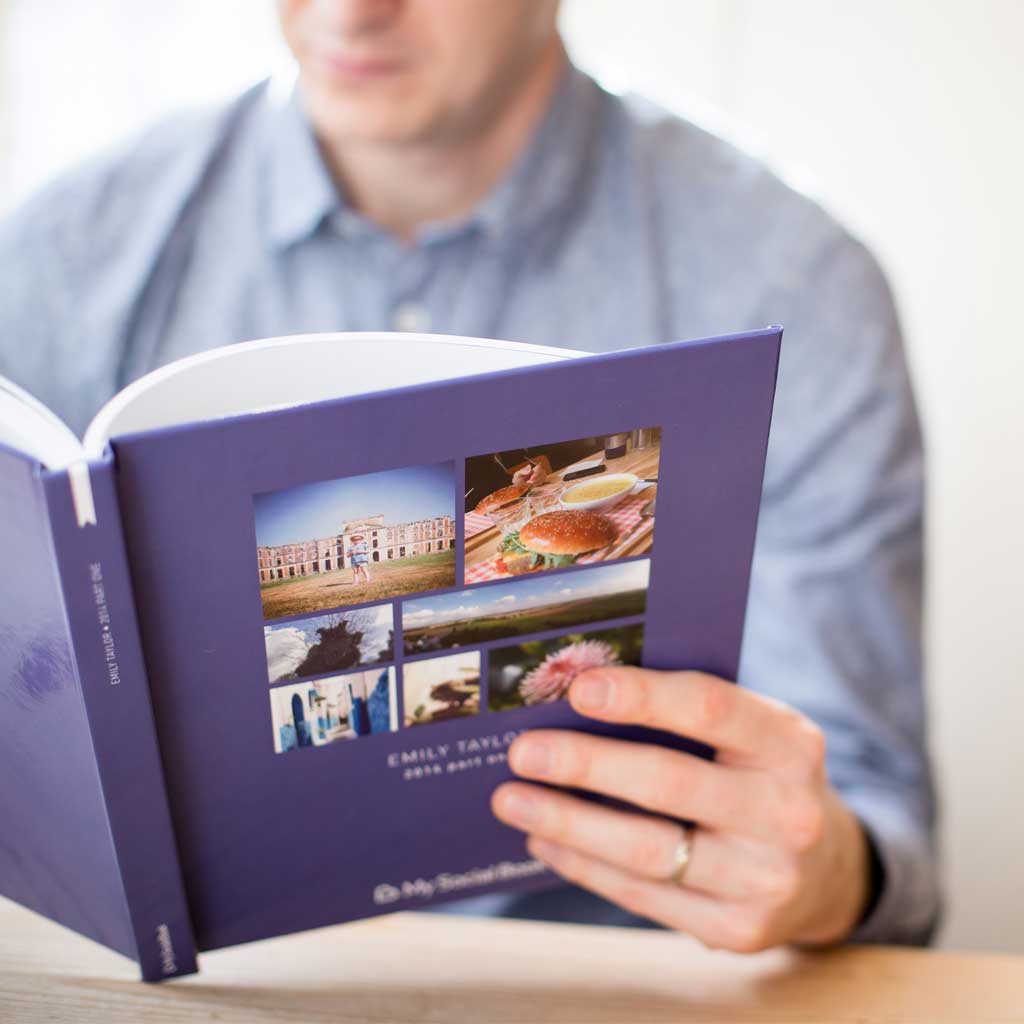 Facebook Page photo book — open book showing imported business page posts in chronological order